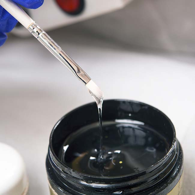 A gloved hand dips a brush into gel—essential for rebalances by The Nail Department and more.