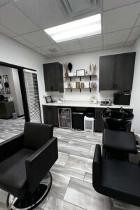 Modern hair salon with black chairs, dark cabinets, and skilled cosmetologists for skincare.