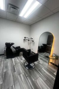 Modern hair salon room with black chairs, washing station—plus The Nail Department and More.