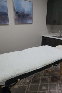 A massage table with a white cover in a spa room for skincare and rebalance treatments.