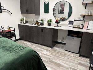 Modern spa room with dark cabinets, green blanket, and decor fit for Cosmetologists.