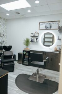 Modern hair salon with styling chair, mirror, and Cosmetologists from The Nail Department and More.