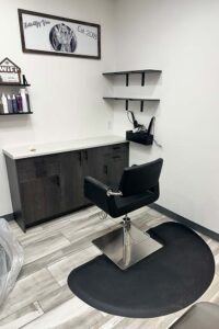 A modern salon station by The Nail Department and More, with black chair and nail enhancements on display.