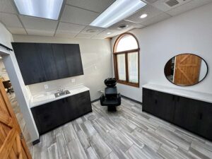 Modern salon room with a wash station, dark cabinets, and skincare at The Nail Department and More.