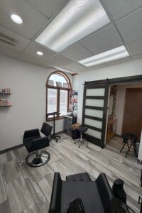 Modern hair salon room with black chairs, tiled floor, and The Nail Department and More.