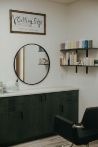 Modern hair studio with a round mirror, product shelves, and expert cosmetologists on-site.