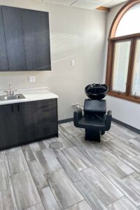 Modern salon room with black hair washing station, sink, and natural nail care service options.