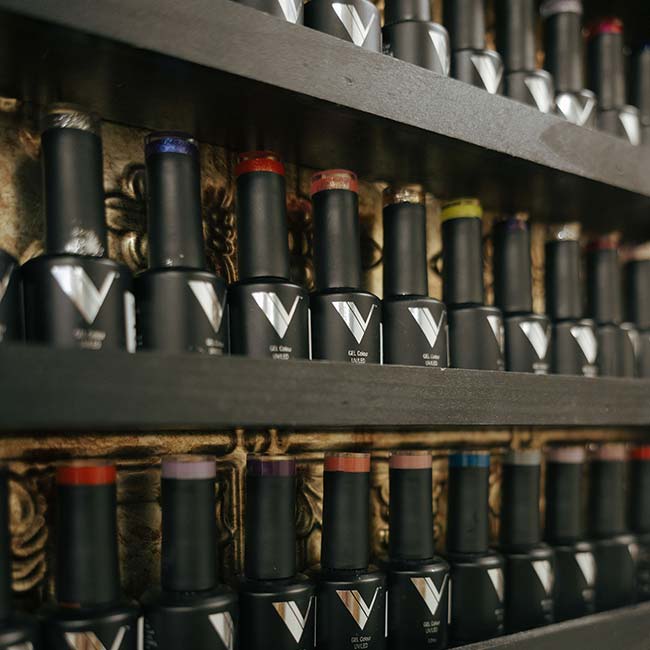 Rows of colorful nail polish bottles at The Nail Department and More, perfect for nail enhancements.