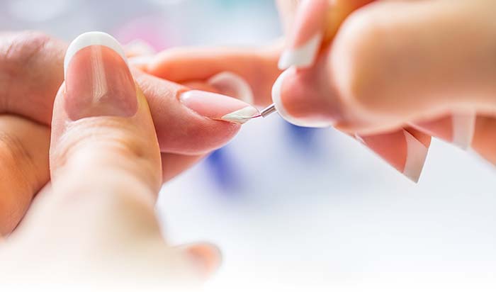 Close-up at The Nail Department and More: applying white polish for natural nail care.